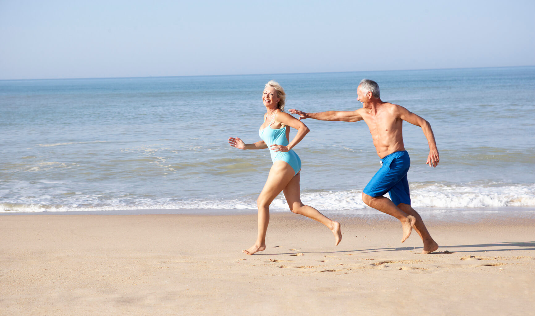 Пожилая пара на пляже бегут